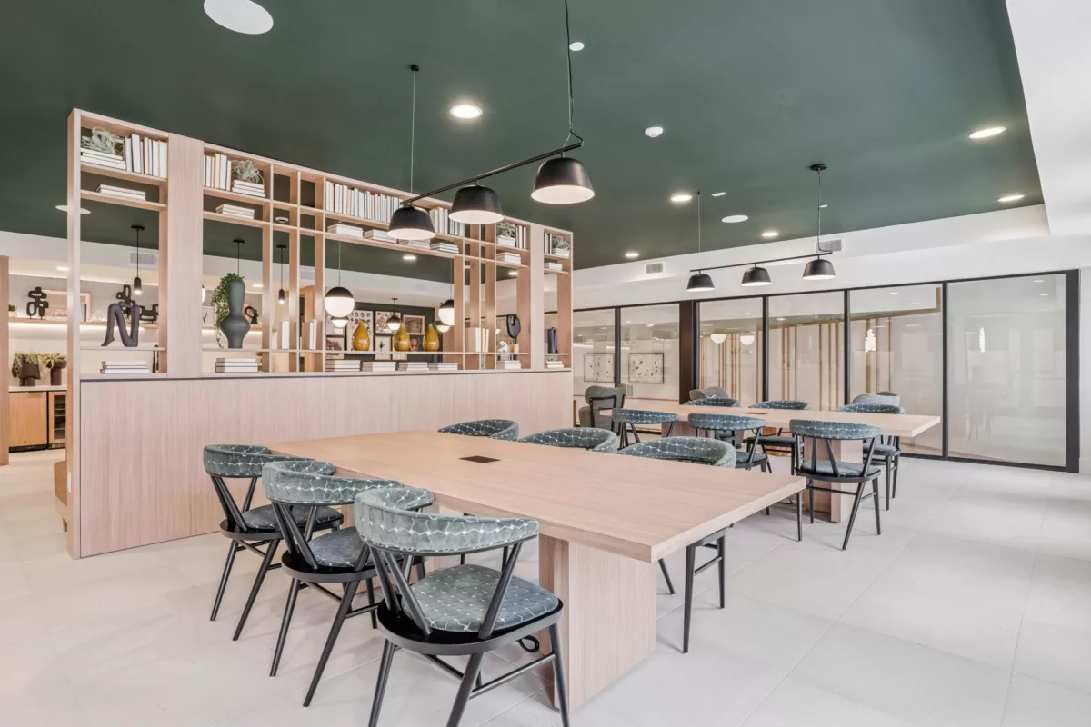 Coworking space with tables, chairs, and shelving filled with books and decor.