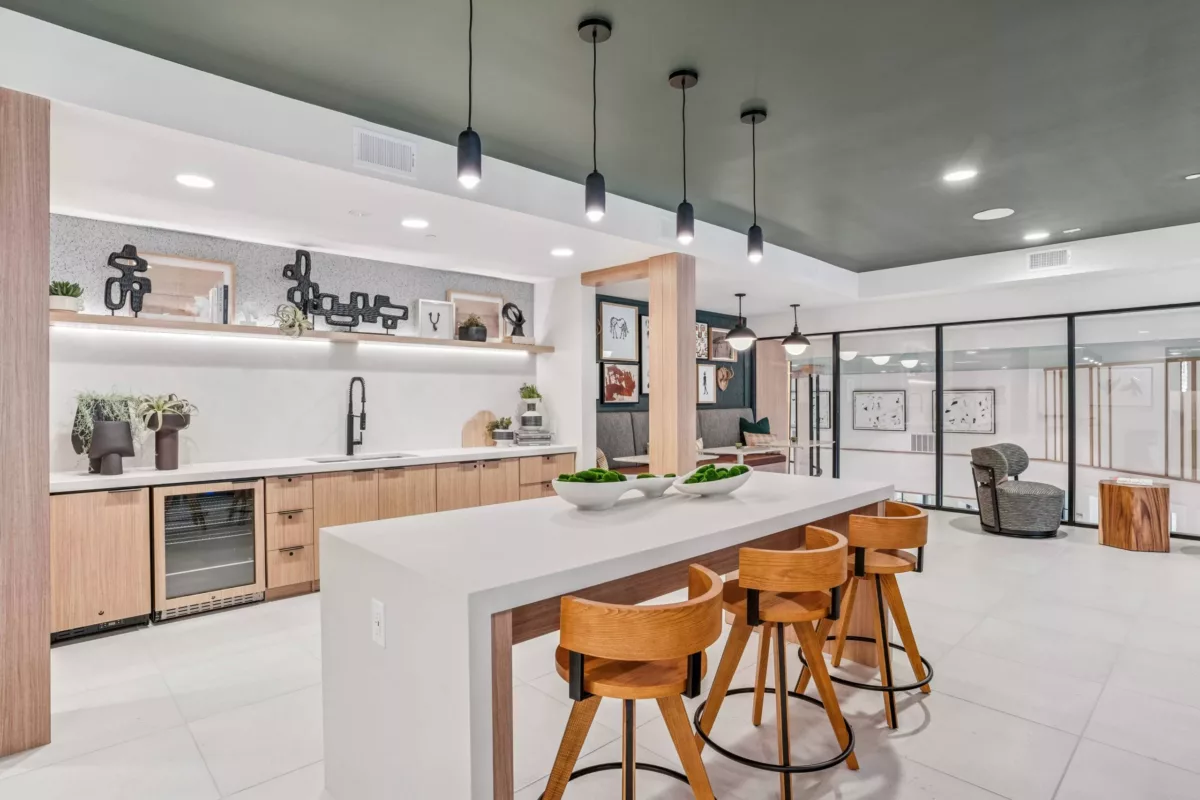 Coworking lounge with island seating, wood cabinets, and decorative shelving.