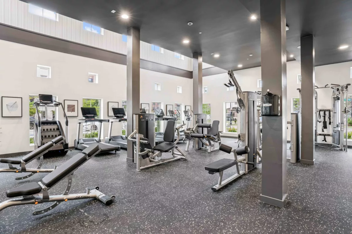 Fitness center with treadmills, weight machines, and rubber flooring.