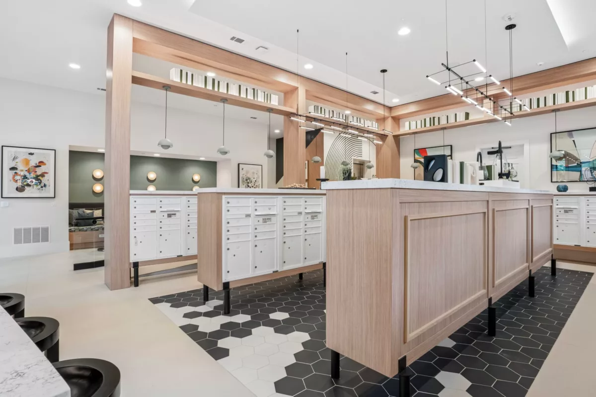 Social mailroom with white mailboxes, wood accents, geometric tile flooring, and contemporary lighting.