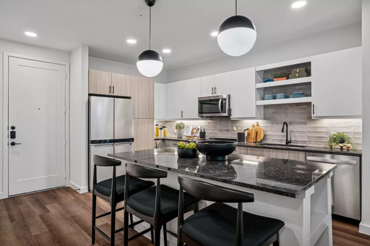 Modern kitchen with granite island, stainless steel appliances, and pendant lighting.