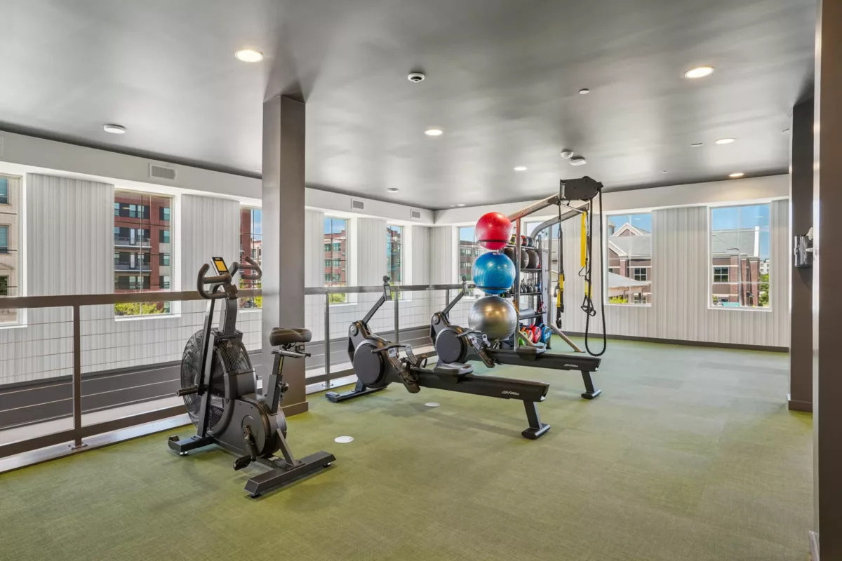 Fitness center with stationary bike, rowing machines, and weight training equipment.
