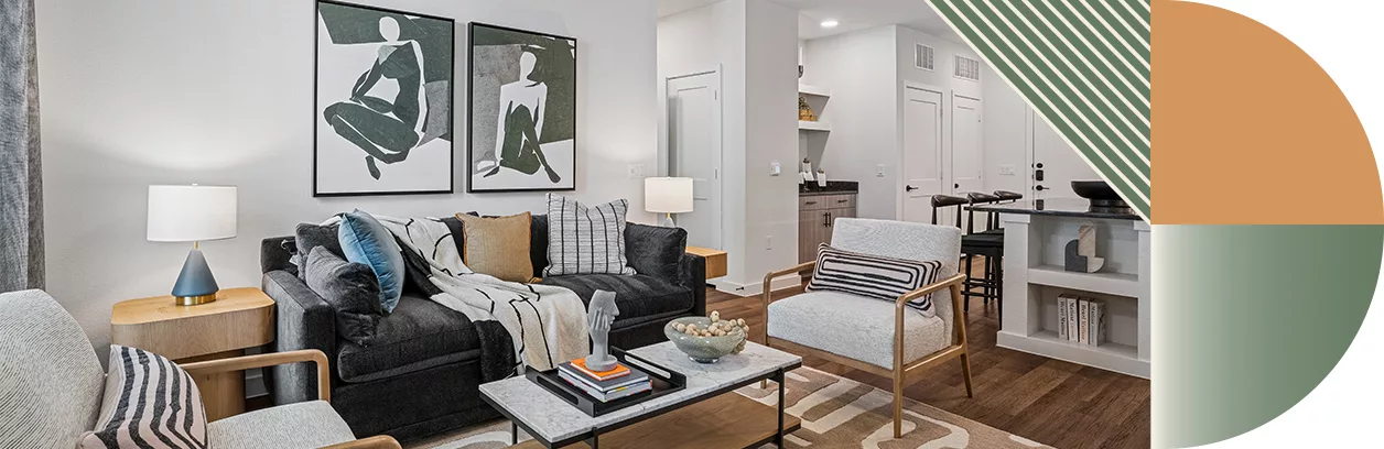 A living room with white walls, wood floors, a gray couch with pillows, arm chairs, and a coffee table.