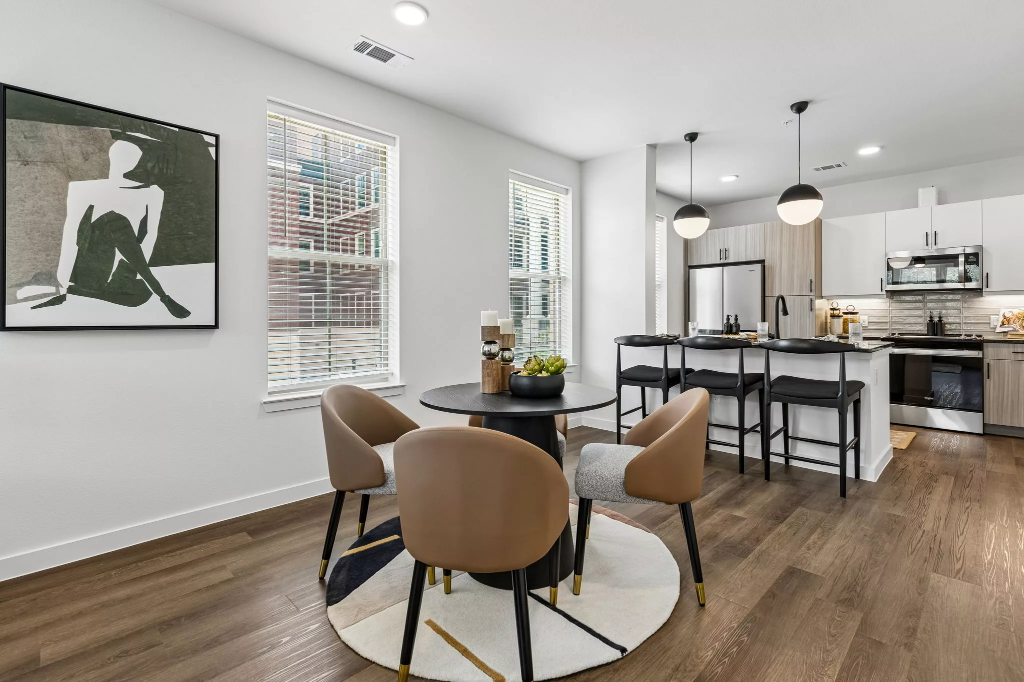 Modern dining area with round table, four chairs, windows, and open kitchen island
